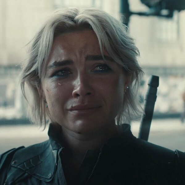 Zbliżenie na twarz kobiety o krótkich, jasnych włosach, wyrażającej intensywny smutek lub ból; po jej policzku spływa łza, a na ramieniu widoczna jest rękojeść miecza, co sugeruje scenę z filmu akcji lub dramatu. Ta pełna emocji i wysokiej jakości wizualnej scena z pewnością należy do tego typu produkcji, które widzowie będą zaliczać do najlepszych filmów 2025 roku. Mimika i dramatyzm kadru sugerują, że to kluczowy moment fabuły, gwarantujący mocne przeżycia kinowe.