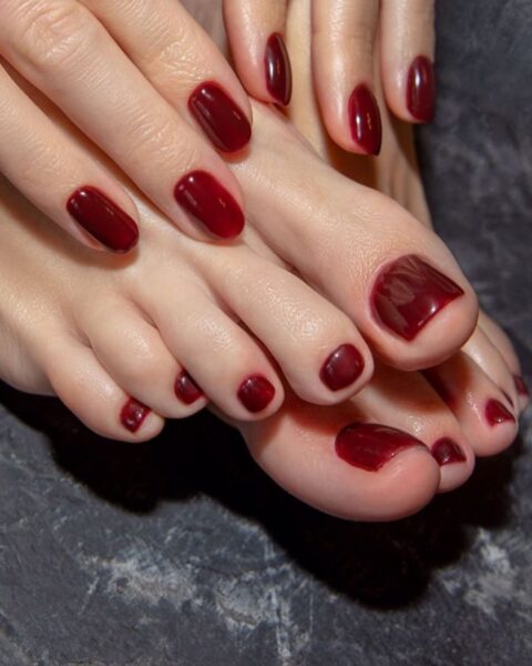 luksusowy żurawinowy pedicure w odcieniach wiśni i bordo, idealnie dopasowany do eleganckiego manikiuru (długie paznokcie w stylu french lub krótkie w kolorze bordo) oraz luksusowego obuwia z logo. Zdjęcia podkreślają spójny look w stylizacji paznokci u dłoni i stóp, idealny dla kobiet z klasą.