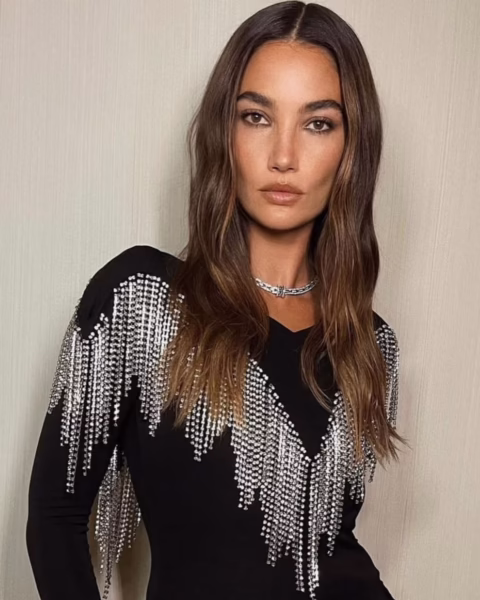 Lily Aldridge w czarnej sukni zdobionej kaskadami lśniących kryształków, prezentująca modny kolor włosów brązowe złoto z przedziałkiem na środku i subtelnymi falami.