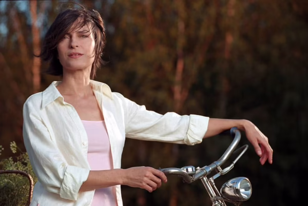 Kadr z filmu „Nigdy w życiu!” przedstawiający Judytę stojącą z rowerem w plenerze, w spokojnym, codziennym otoczeniu. Obraz podkreśla motyw życiowego resetu bohaterki i dobrze ilustruje temat polskich odpowiedników kultowych zagranicznych filmów, porównywanych do „Dziennika Bridget Jones”.