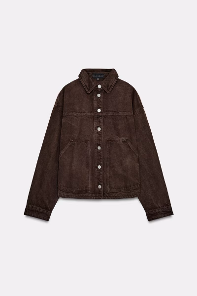 Zdjęcie produktowe brązowej kurtki jeansowej Zara Z1975. Model ma luźny krój, klasyczny kołnierzyk, srebrne guziki oraz duże naszywane kieszenie z przodu. Ciemny, czekoladowy odcień denimu nadaje kurtce wyraźnie jesienny charakter.